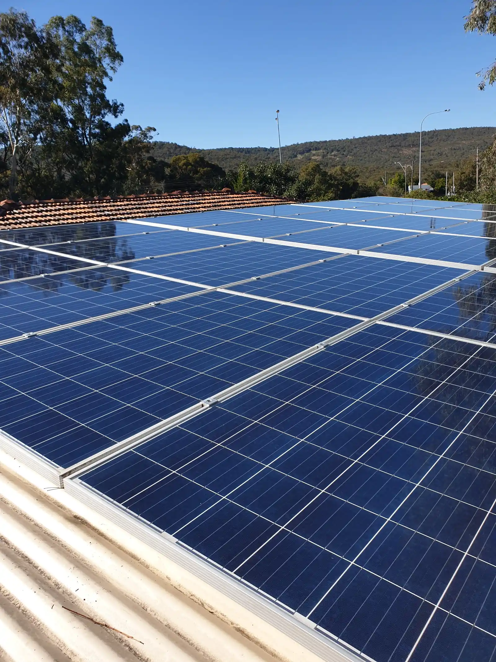 A cleaned solar array on a corrugated roof with the Perth hills in the background