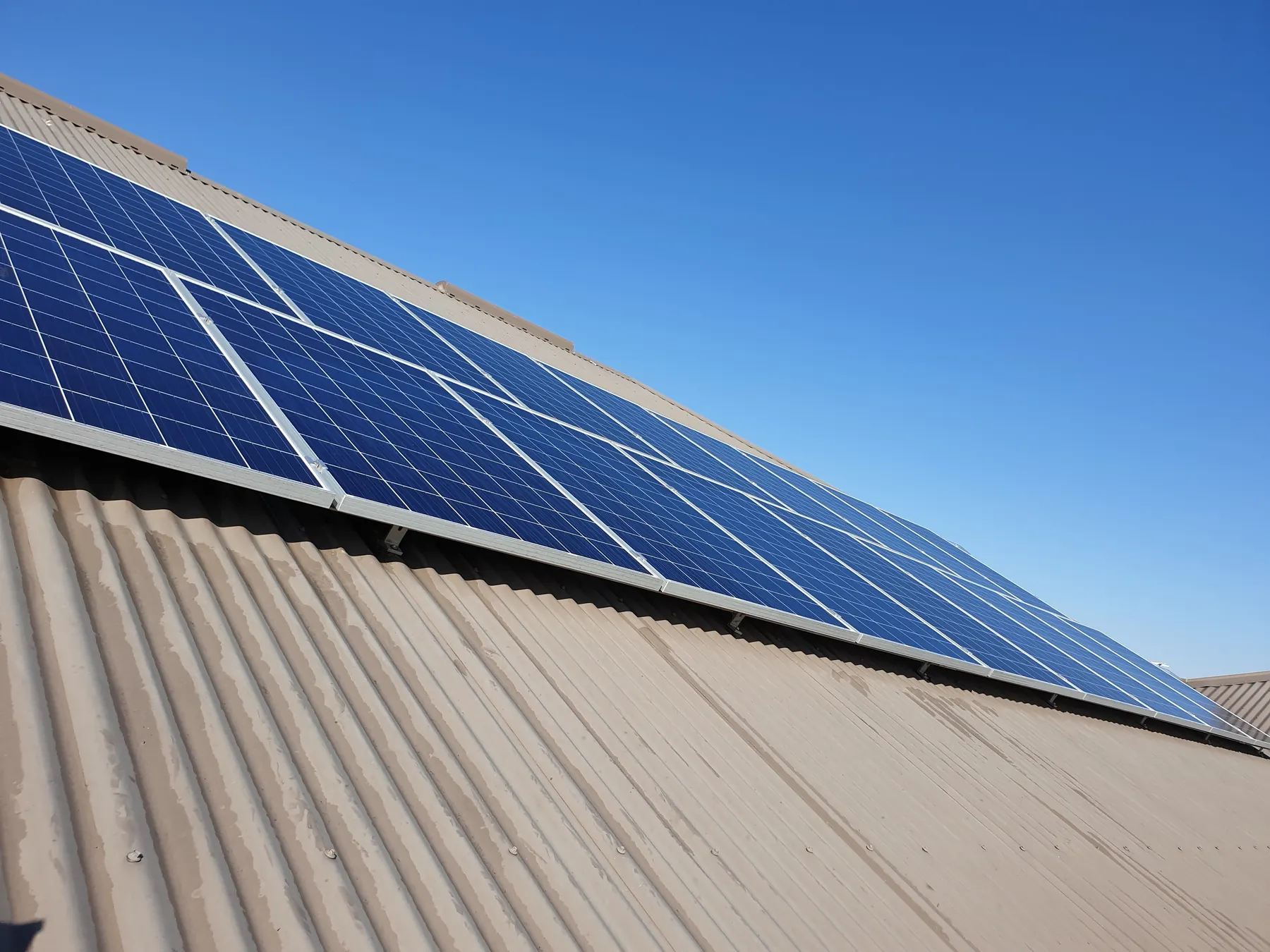 Freshly cleaned solar panels on a corrugated iron roof under a clear Perth sky