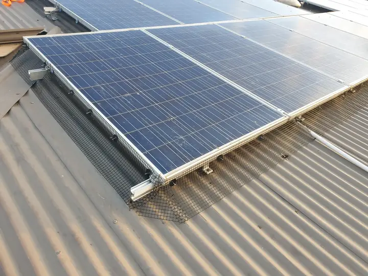Bird proofing mesh along the edge of solar panels on a tin roof