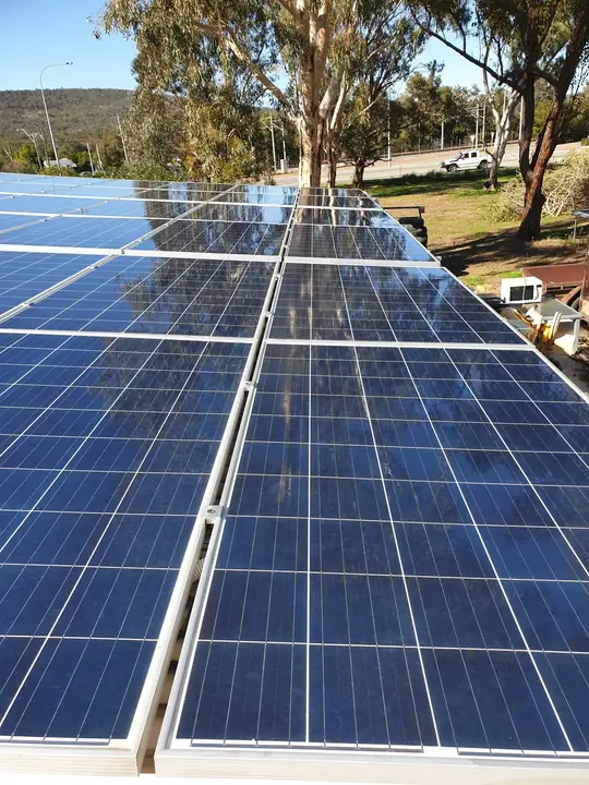 A large cleaned solar array reflecting trees on a tin roof